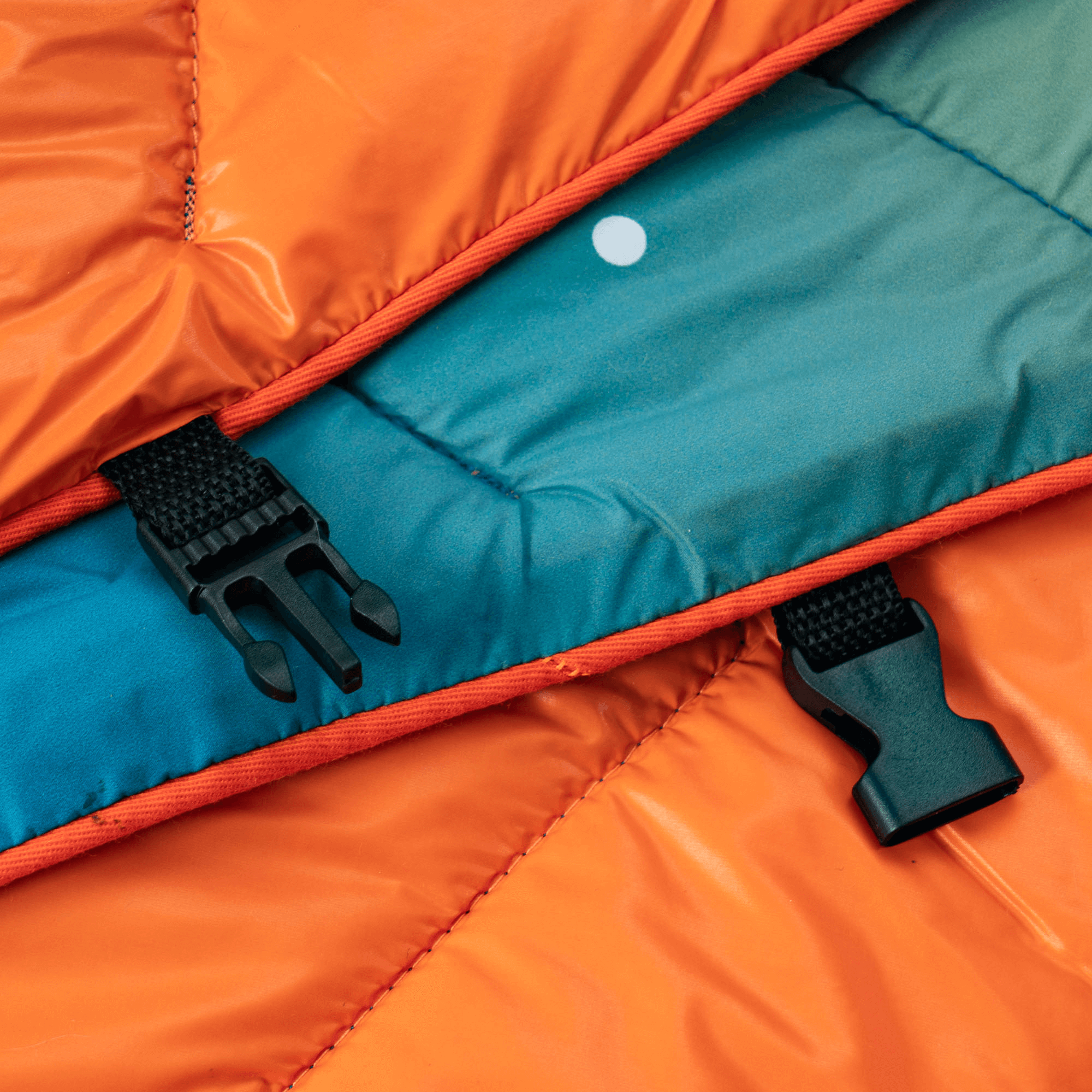 Close-up of durable plastic buckle and nylon webbing straps on a puffy outdoor blanket, premium workmanship for outdoor gear brands.