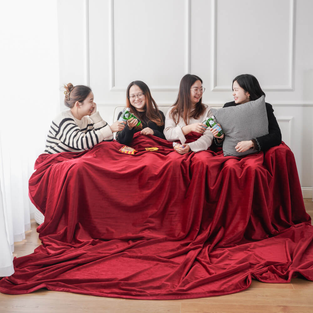 Four women enjoying a cozy night with a seamless minky fleece blanket. Ideal wholesale soft plush blanket for home comfort.