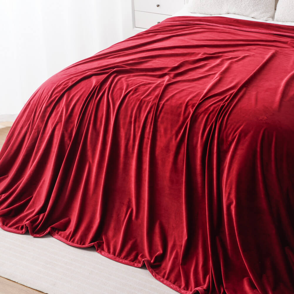 Red seamless minky fleece blanket draped over bed, soft and lightweight