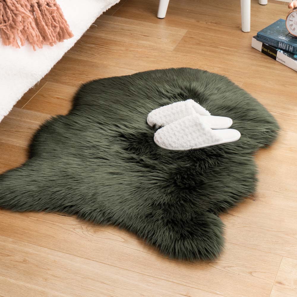 Thick dark green faux sheepskin rug used as a bedside floor mat with white slippers, available for home textile wholesale.