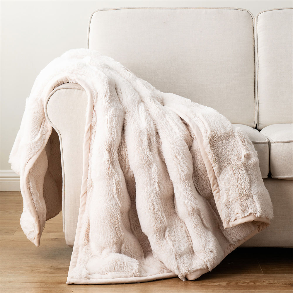 Soft light pink double-sided ripple faux fur blanket draped over a modern white sofa, ideal for cozy home decor wholesale.