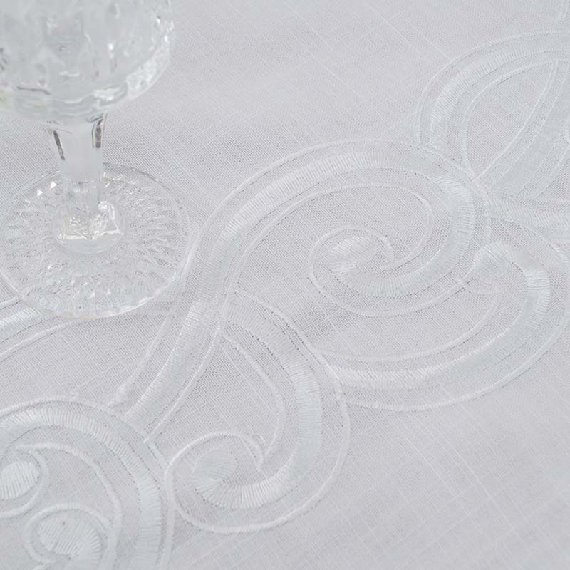 Detail view of high-quality white embroidery craftsmanship and scalloped edge on premium table linen