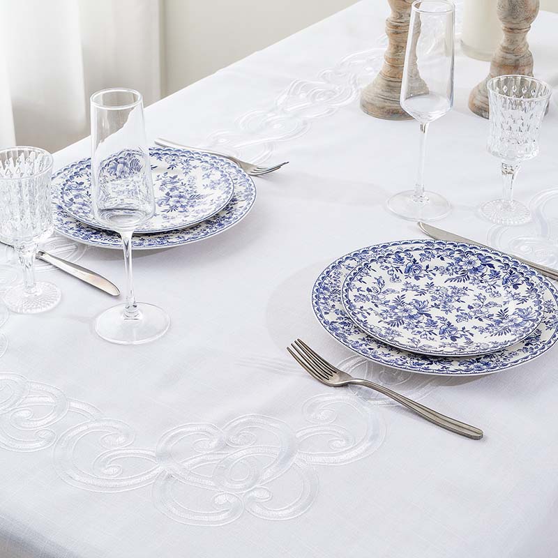 Close-up of elegant embroidery tablecloth decorated with classic dinnerware for event rental inspiration