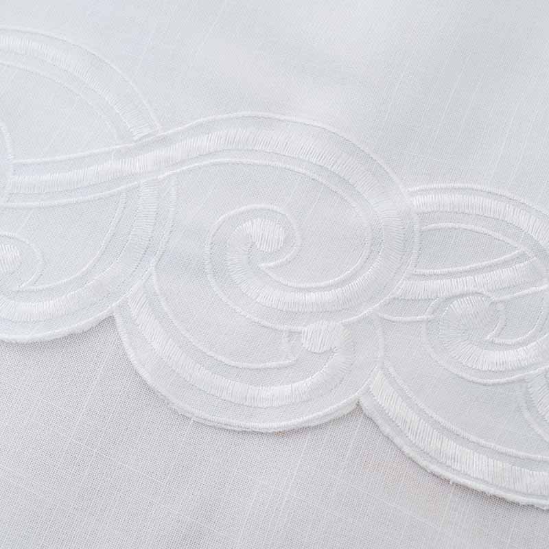 Close-up shot of the exquisite custom embroidery pattern and scalloped border on the tablecloth