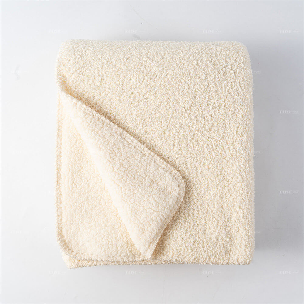 Top view flat lay of folded cream microfiber chenille reversible throw blanket on a white surface.
