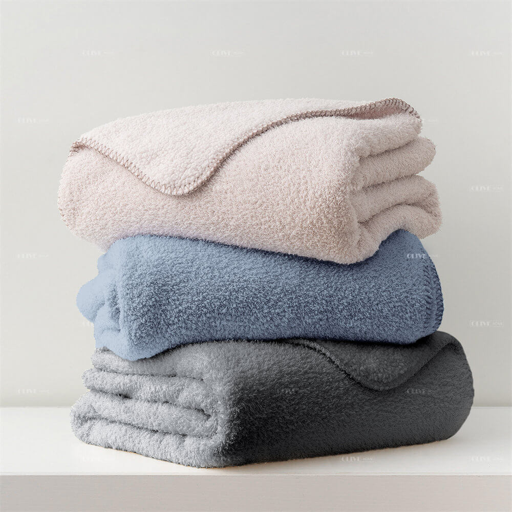Stack of microfiber chenille reversible throw blankets in pink, blue, and dark grey for wholesale.