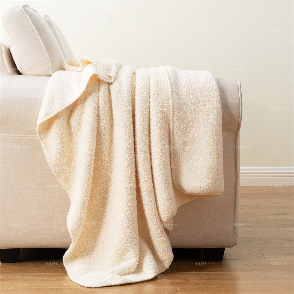 Premium cream microfiber chenille reversible throw blanket elegantly draped over a modern sofa couch.