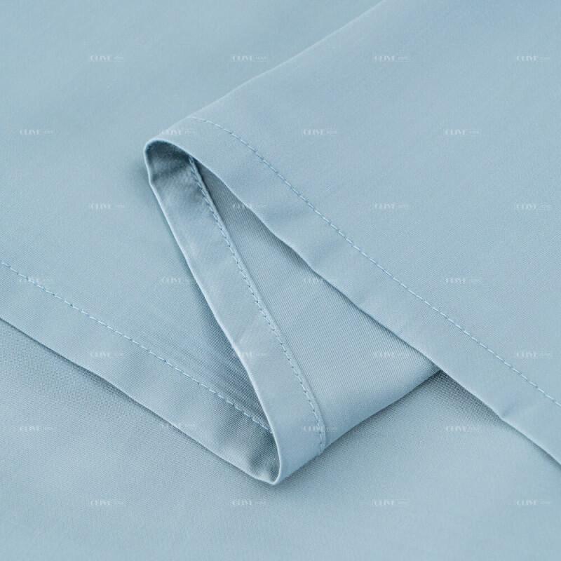 Detailed shot of the professional neat stitching and wide hem line on the edge of a light blue organic bamboo flat sheet.