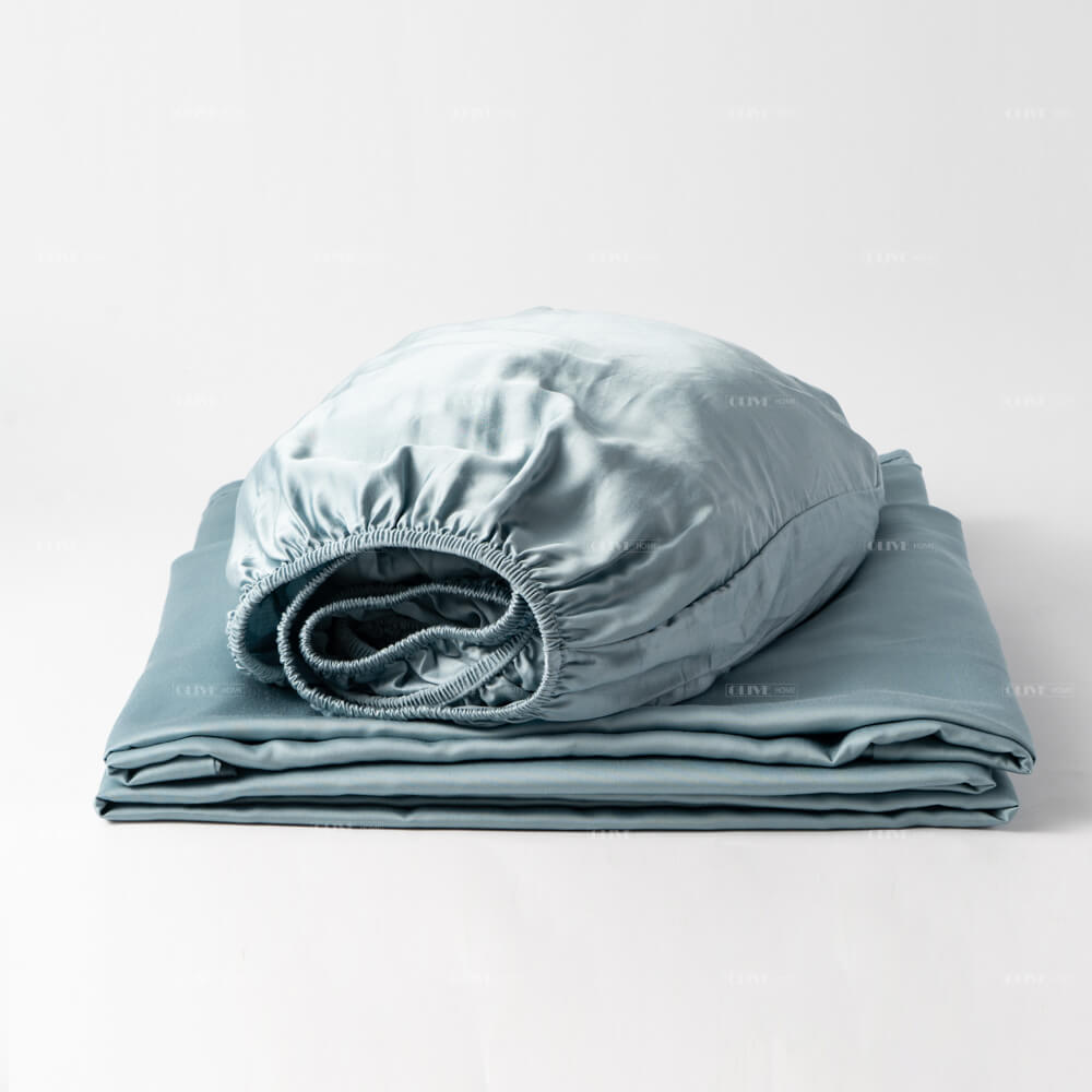 Neatly folded 100% organic bamboo cooling bed sheet set in light blue, displaying the silky texture of the flat sheet and elastic fitted sheet.