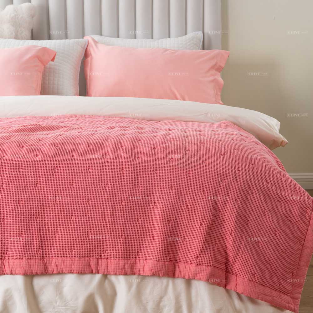 Peachy Pink Mills waffle cotton quilt neatly spread on a bed with dot quilting pattern and matching pink pillow shams