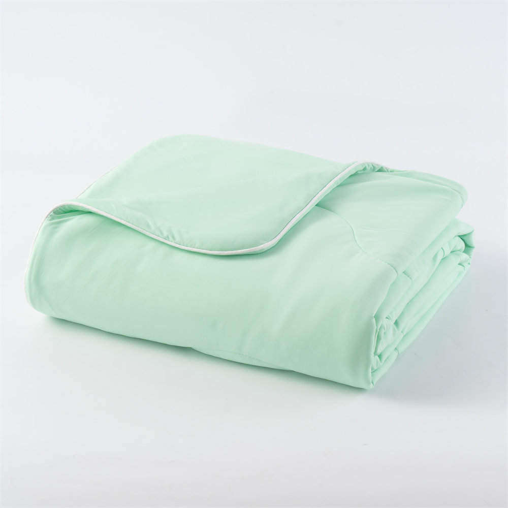 Folded mint green lightweight cooling comforter with white piping border, perfect for commercial hospitality and bulk retail distribution
