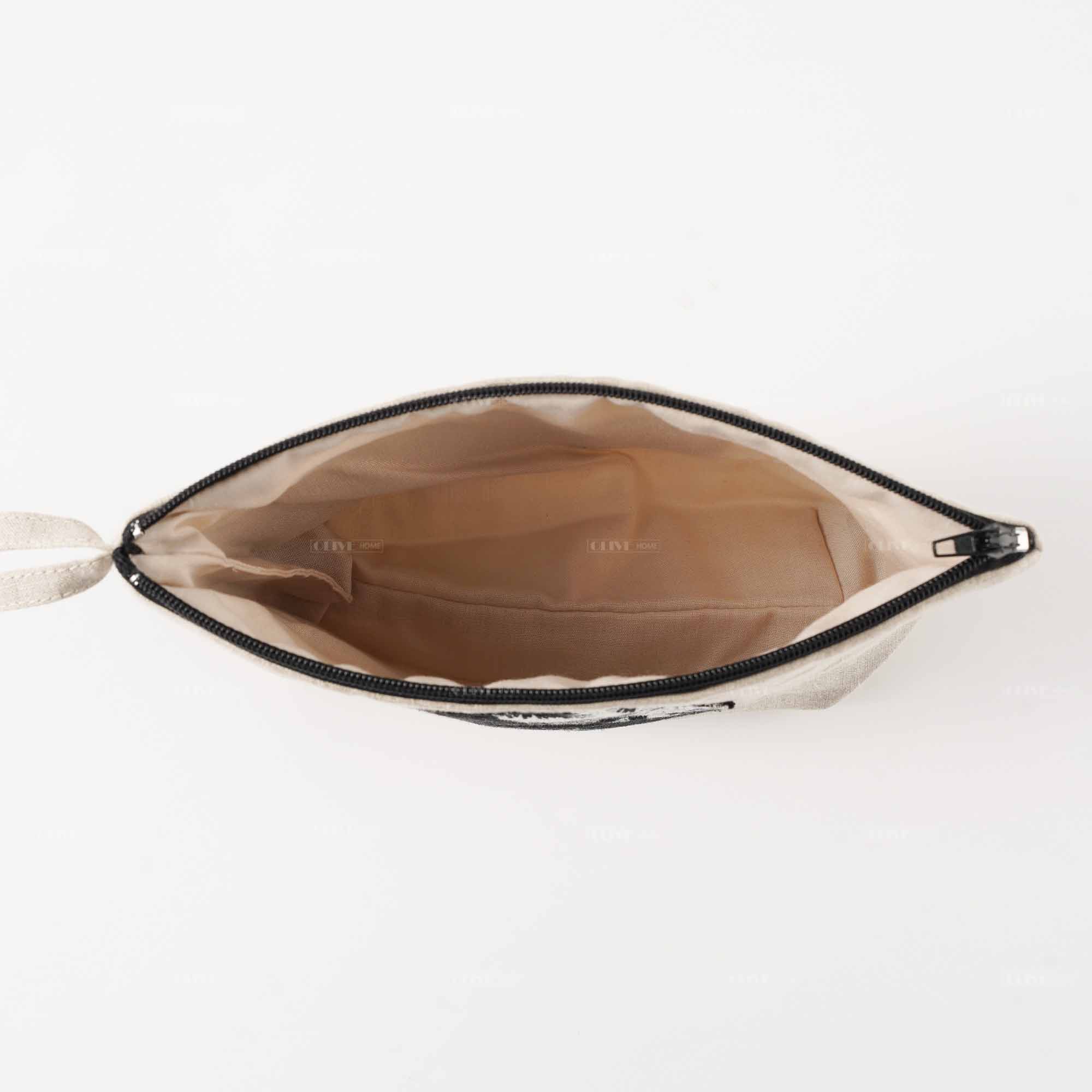 Inside look of an open linen clutch bag with handle, showing smooth fabric lining and ample space for cosmetics.