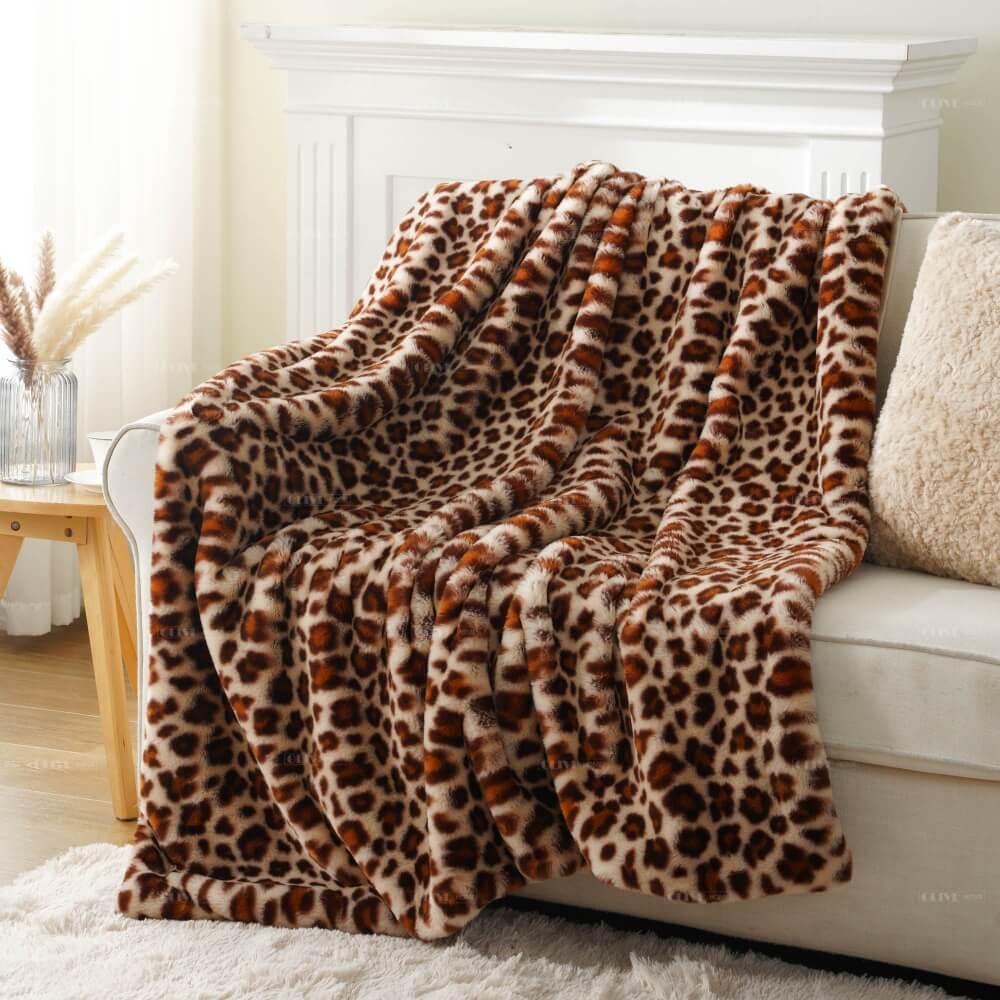 Leopard pattern cloud-like faux fur throw blanket fully displayed on a couch, available for bulk supply from Olive Home.
