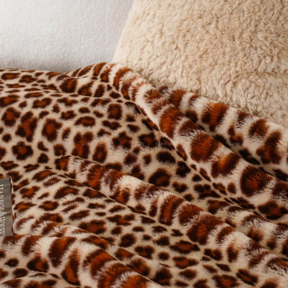 Lifestyle view of leopard print faux fur blanket on a bed, premium zero shed soft throw blanket for wholesale suppliers and distributors.